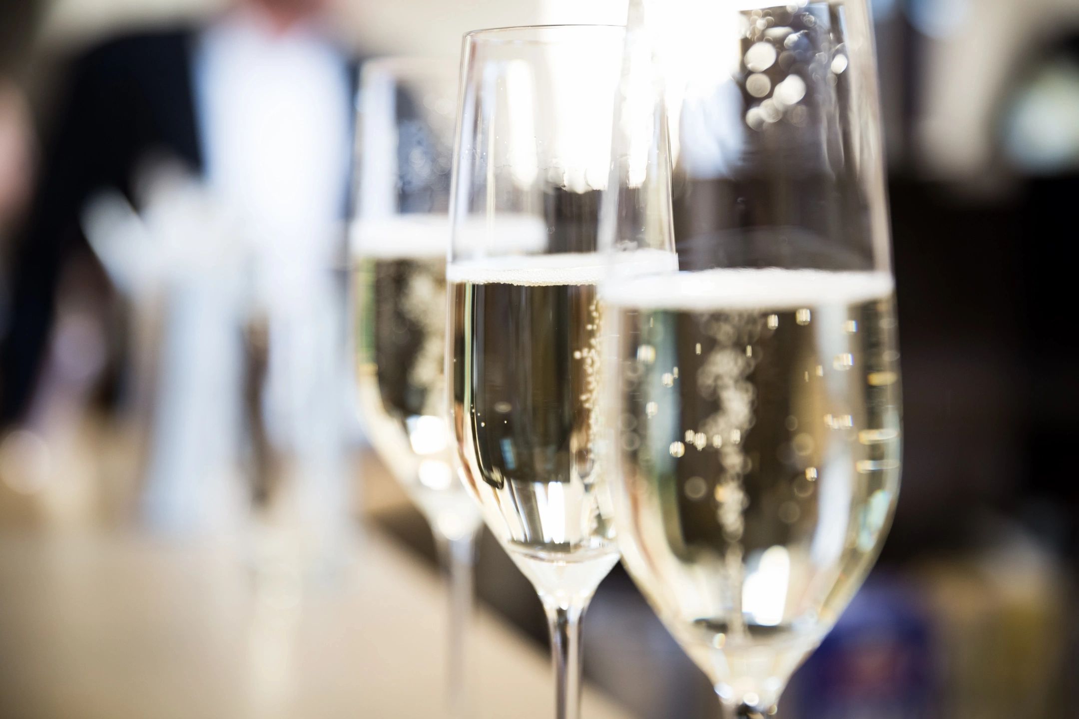 Two champagne glasses clinking in a bright setting, symbolizing friendship and community gatherings.